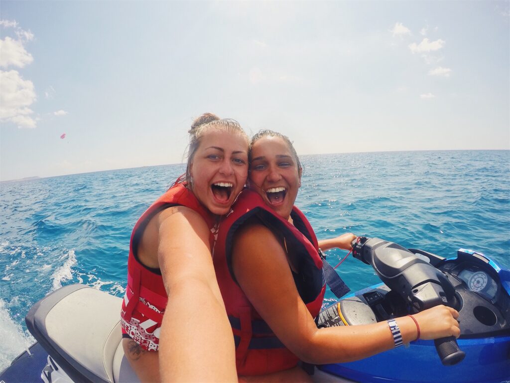 Women Best friends lesbian couple on vacation doing water sports on jet ski in ocean