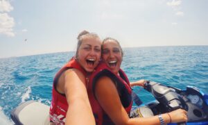 Women Best friends lesbian couple on vacation doing water sports on jet ski in ocean