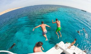 Two men jump into the sea from a yacht. Friends are having fun on vacation.